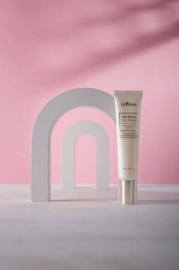 İzmail, Ukrayna. Temmuz 2024. Pembe arka planda, beton dekoratif elementlerle Kore kozmetik tüpü. ISNTREE tonu ve kırışık göz kremi.