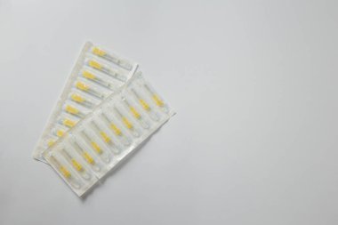 Beyaz arka planda plastik paketin içine şırınga iğneleri yerleştirildi. Enjeksiyon, aşı ya da kozmetoloji için tıbbi ekipman. Boşluğu kopyala.