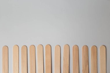 Balmumu tütsüleme ya da şekerleme için tek kullanımlık birkaç tahta spatula, beyaz arka planda alt sınırı oluşturur. Güzellik prosedürleri, cilt bakımı. Boşluğu kopyala.