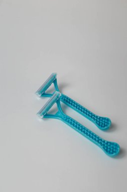 İstenmeyen kıllar için mavi tek kullanımlık tıraş bıçağı, beyaz arka planda tüy dökülmesi. Üst görünüm, boşluğu kopyala. Dikey çekim