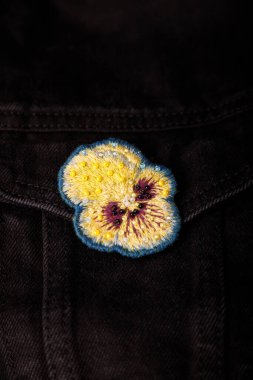 Yumuşak, kalp kaplaması nakış işlemeli siyah kot pantolon kumaş arka planda boncuklar, yakın çekim, uzay kopyalama.