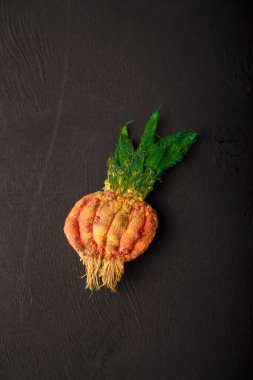 Siyah ahşap arka planda kumaş yeşili soğan broşu. Geri dönüşüm ve yükseltme konsepti. Pamuk kumaştan komik bir aksesuar. Boşluğu kopyala.