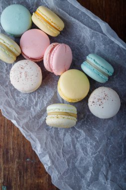 Kağıt üzerinde farklı tatlara sahip yumuşak renkte badem kurabiyeleri, ahşap kırsal arka plan. Üst görünüm, alanı kopyala