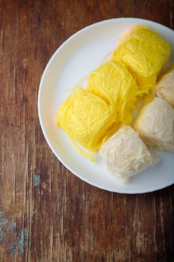 Pismaniye, pamuk helva veya ejderha sakalı vanilyalı ve kavun tadı beyaz tabakta, ahşap arka planda. Türk tatlısı, hafif helva, pamuk helva. Üst görünüm, alanı kopyala