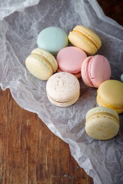 Kağıt üzerinde farklı tatlara sahip yumuşak renkte badem kurabiyeleri, ahşap kırsal arka plan. Üst görünüm, alanı kopyala