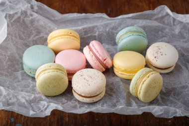 Kağıt üzerinde farklı tatlara sahip yumuşak renkte badem kurabiyeleri, ahşap kırsal arka plan. Yakın çekim.