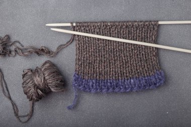 Gri arka planda örgü ören kumaşlar, saç örgüsü ve akrilik iplik topları..