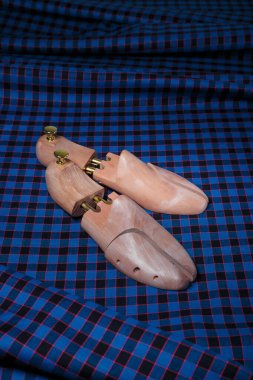 Ahşap ayakkabı blokları, ayakkabı kalıpları ya da mavi kareli takım elbise kumaş arka planı üzerindeki sedyeler, kopyalama alanı.