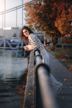 Moda kıyafetleri içinde gülümseyen genç ve güzel bir hippi kadın. Günbatımında Avrupa sokaklarında poz veren seksi tasasız model. Pozitif esmer kadın. Neşeli ve mutlu