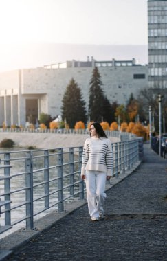 Moda kıyafetleri içinde gülümseyen genç ve güzel bir hippi kadın. Günbatımında Avrupa sokaklarında poz veren seksi tasasız model. Pozitif esmer kadın. Neşeli ve mutlu