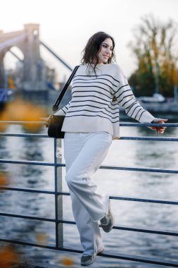 Moda kıyafetleri içinde gülümseyen genç ve güzel bir hippi kadın. Günbatımında Avrupa sokaklarında poz veren seksi tasasız model. Pozitif esmer kadın. Neşeli ve mutlu