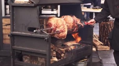 a piece of meat is fried on a spit on a street party. Christmas celebration in the city. Food festival. Street food.