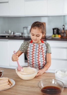 Tiramisu mutfakta işlem yapıyor. Küçük kız kakao ve mascarpone kremalı espresso soslu kadın parmaklarıyla İtalyan çölü yapıyor.)