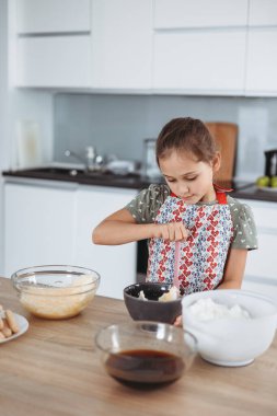 Tiramisu mutfakta işlem yapıyor. Küçük kız kakao ve mascarpone kremalı espresso soslu kadın parmaklarıyla İtalyan çölü yapıyor.)