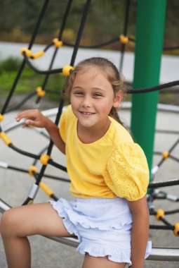Okul bahçesindeki çocuk. Küçük kızın anaokulu oyun parkında spor salonu var. Çocuklar için sağlıklı bir açık hava aktivitesi. Küçük çocuklar için spor