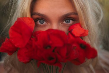 Kadın gözlerinin ve kırmızı gelincik çiçeklerinin yakın çekimi