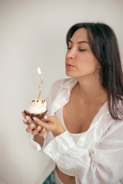 Doğum günü pastasında mum üfleyen genç bir kadın. Doğum günü kutlaması