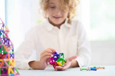 Manyetik sopalarla ve yapı taşlarıyla oynayan bir çocuk. Küçük çocuk kule inşa ediyor. Çocuklar için eğitici oyuncaklar. Küçük çocuklar için inşaat oyuncakları. Geometri ve matematik oyunu. Okul öncesi eğlencesi.