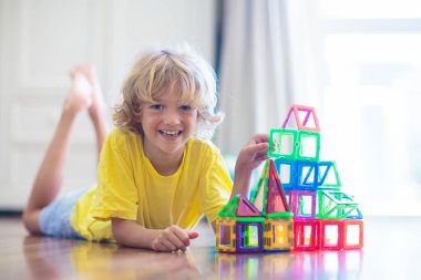 Çocuk manyetik yapı taşlarıyla oynuyor. Küçük çocuk kule inşa ediyor. Çocuklar için eğitici oyuncaklar. Küçük çocuklar için inşaat oyuncakları. Geometri ve matematik oyunu. Okul öncesi eğlencesi.