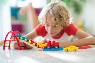 Çocuklar oyuncak tren yolu ile oynarlar. Çocuk renkli gökkuşağı ahşap trenleriyle oynuyor. Küçük çocuk için oyuncaklar. Anaokulunda ya da anaokulunda demiryolu inşaatı yapan anaokulunda. Anaokulu eğitim oyunları.