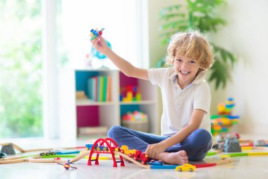 Çocuklar oyuncak tren yolu ile oynarlar. Çocuk renkli gökkuşağı ahşap trenleriyle oynuyor. Küçük çocuk için oyuncaklar. Anaokulunda ya da anaokulunda demiryolu inşaatı yapan anaokulunda. Anaokulu eğitim oyunları.