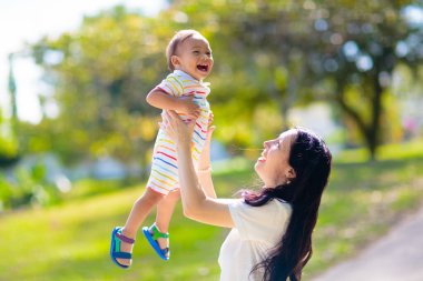 Sunny Park 'ta anne ve oğlu. Dışarıda oynayan Asyalı bir aile. Anne kucağında küçük bir çocuk var. Genç bir kadın ve sevimli bir çocuk oynuyorlar ve gülüyorlar. Mutluluk ve sevgi. Anneler günün kutlu olsun..