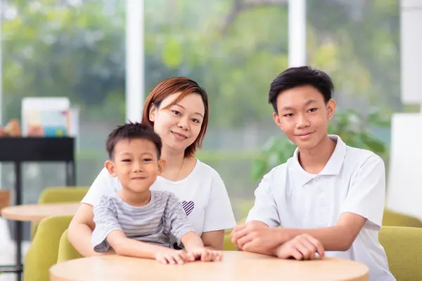 レストランのママと子供たち アジアの家族が外食する 白い晴れた部屋で美しい若い母と2人の少年 ロイヤリティフリーのストック画像