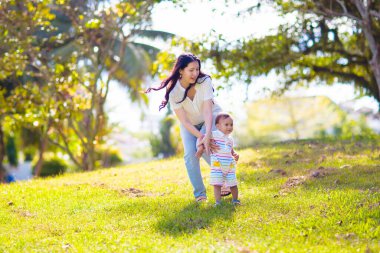 Sunny Park 'ta anne ve oğlu. Dışarıda oynayan Asyalı bir aile. Anne kucağında küçük bir çocuk var. Genç bir kadın ve sevimli bir çocuk oynuyorlar ve gülüyorlar. Mutluluk ve sevgi. Anneler günün kutlu olsun..