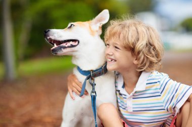 Çocuk sonbahar parkında köpeğiyle oynuyor. Çocuklar ve köpekler. Küçük çocuk güneşli arka bahçede hayvanına sarılıyor. Hayvan bakımı. Aşk ve arkadaşlık. Aile hayvanları. Yavru köpek.