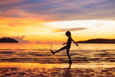 Okyanus sahilinde oynayan bir çocuk. Gün batımında dalgalara atlayan bir çocuk. Aile için deniz tatili. Yaz tatili boyunca egzotik adada koşan küçük çocuk.. 