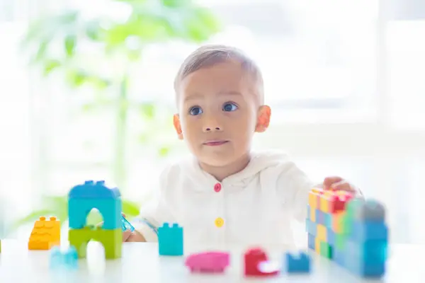 白い晴れた寝室でカラフルなブロックのおもちゃで遊ぶ愛らしいアジアの赤ん坊の男の子 教育玩具を持ったかわいい赤ちゃん チャイルドビル塔 スマートな子供のための早期開発 保育園 楽しい ストック写真