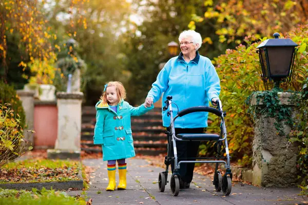 歩行器や車椅子の子供と幸せなシニア女性 祖母と子供を公園で散歩を楽しんでいます 子のサポートには 祖父母が無効になります 家族をご覧ください 世代の愛との関係 ストック画像