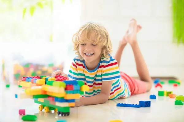 子供たちはカラフルなブロックで遊ぶ 自宅やデイケアで小さな男の子の建物の塔 子供のための教育玩具 赤ちゃんや幼児の子供のための建設創造的なゲーム 幼稚園の遊び場でメス ストックフォト