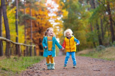 Çocuklar sonbahar parkta oynamak. Sarı akçaağaç yaprakları atan çocuklar. Erkek ve kız atlamak ve Meşe yaprağı ile çalıştırın. Sonbaharda yapraklar. Güz aile açık eğlence. Yürümeye başlayan çocuk ve okul öncesi çocuk Güz.