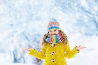 Çocuk örme şapka Noel tatile karda oynarken. Kış açık eğlence. Örgü ve dış giyim aile için. Kids karlı parkta oynamak. Küçük kız örgü atkı ve kar taneleri yakalamaya eldivenler.