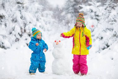 Çocuklar kardan. Kar bina çocuklar oynarken açık havada güneşli karlı kış gün dostum. Noel tatil açık aile eğlencesi. Erkek ve kız kar topları oyun. Kış giyim bebek ve yürümeye başlayan çocuk için.