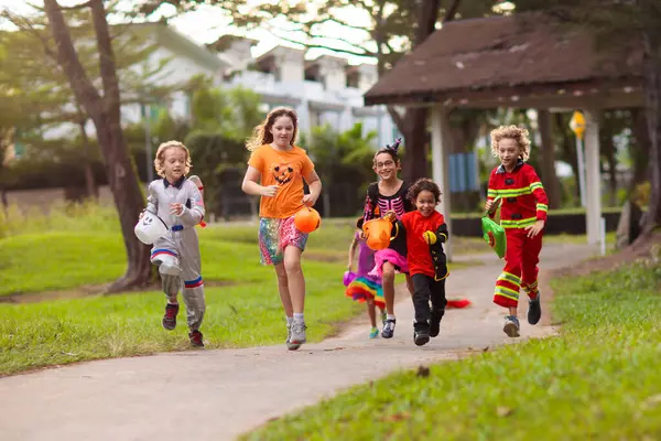 ハロウィーンのコスチューム 混合されたレースの子供や親は 路上でトリックまたは治療します カボチャランタンとキャンディーバケツを持つ小さな男の子と少女 魔女の帽子をかぶった赤ちゃん 秋の休日 楽しい ストック写真