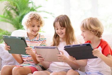 Cep telefonu olan çocuklar. Tabletli çocuk film izliyor ya da oyun oynuyor. Dijital cihazı ve aleti olan bir grup küçük çocuk. Küçük çocuk için ekran zamanı ve eğitim. Arkadaşlar oynar.
