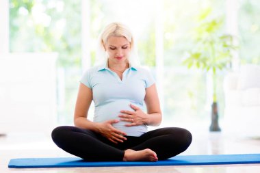 Hamilelik yogası. Hamile kadın için egzersiz. Evde ya da spor salonunda spor yapan aktif genç bir bayan. Yeni hamile anne doğumdan önce aktif ve zinde. Annemi beklediğim için spor. Çevrimiçi sınıf.