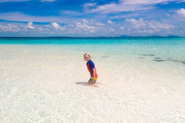 Tropik plajda oynayan çocuklar. Çocuklar yaz tatilinde yüzer ve denizde oynarlar. Kum ve su eğlencesi, küçük çocuklar için güneş koruması. Okyanus kıyısında koşan ve zıplayan küçük çocuk.