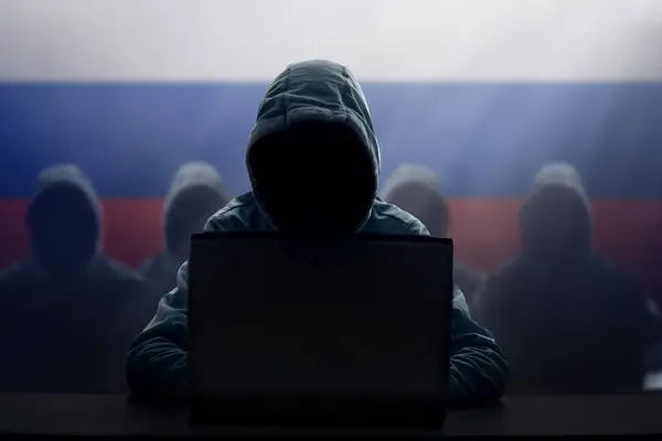 stock image Russian hacker at laptop. Malware and virus danger from Russia. Man in hoodie and dark mask hacking. Dark net and cyber crime. Identity theft. Criminal at work. Troll army. 