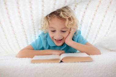 Çocuk yatakta örülmüş battaniyenin altında kitap okuyor. Çocuklar yatak odası kızlık zarı stili. Küçük çocuk uyumadan önce ödevini yapıyor..