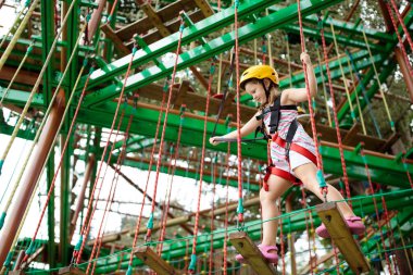 Orman macera parkında bir çocuk. Çocuklar yüksek ip izlerine tırmanıyor. Çeviklik ve çocuklar için açık hava eğlence merkezine tırmanma. Küçük kız dışarıda oynuyor. Okul bahçesinde iple oyun oynanır..