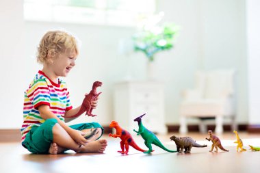 Çocuk renkli oyuncak dinozorlarla oynuyor. Çocuklar için eğitici oyuncaklar. Küçük çocuk fosil ve sürüngen öğreniyor. Çocuklar dinozor oyuncaklarıyla oynarlar. Genç çocuklar için evrim ve paleontoloji oyunu.