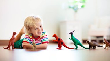 Çocuk renkli oyuncak dinozorlarla oynuyor. Çocuklar için eğitici oyuncaklar. Küçük çocuk fosil ve sürüngen öğreniyor. Çocuklar dinozor oyuncaklarıyla oynarlar. Genç çocuklar için evrim ve paleontoloji oyunu.