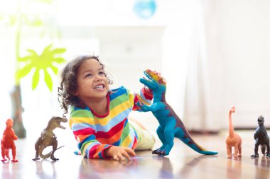 Çocuk renkli oyuncak dinozorlarla oynuyor. Çocuklar için eğitici oyuncaklar. Küçük çocuk fosil ve sürüngen öğreniyor. Çocuklar dinozor oyuncaklarıyla oynarlar. Genç çocuklar için evrim ve paleontoloji oyunu.