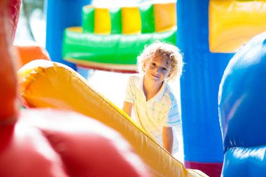 Çocuk renkli trambolinde atlıyor. Çocuklar anaokulundaki doğum günü partisinde şişme şatoya atlayıp küçük çocuklar için oyun merkezine giriyorlar. Küçük çocuk yazın dışarıda oynuyor..