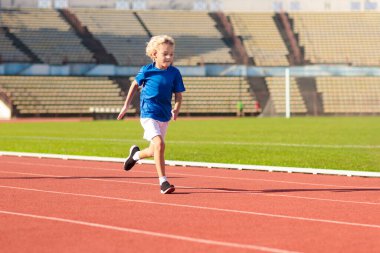 Stadyumda çalışan çocuk. Çocuklar açık pistte çalışır. Çocuklar için sağlıklı spor aktivitesi. Atletizm yarışında küçük kız ve çocuk. Genç atlet eğitimi. Runner egzersiz. Çocuk için jogging.