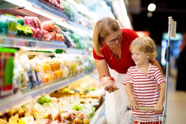 Shopping with kids. Mother and child buying fruit in supermarket. Mom and little boy buy fresh mango in grocery store. Family in shop. Parent and children in a mall choosing vegetables. Healthy food.