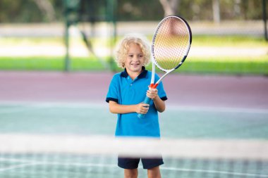 Kapalı kortta tenis oynayan çocuk. Tenis raket ve top spor kulübü küçük çocuk. Çocuklar için aktif egzersiz. Çocuklar için yaz etkinlikleri. Eğitim genç çocuk için. Çocuk oynamak için öğrenme.